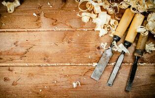 Chisels with wooden shavings. On a wooden background. photo