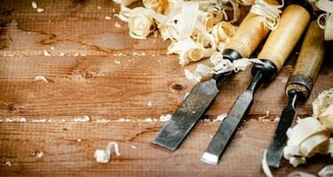 Chisels with wooden shavings. On a wooden background. photo