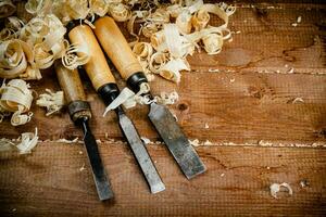 Chisels with wooden shavings. On a wooden background. photo