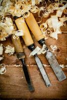 Chisels with wooden shavings. On a wooden background. photo