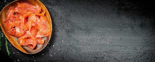 A wooden plate with slices of salted salmon. photo