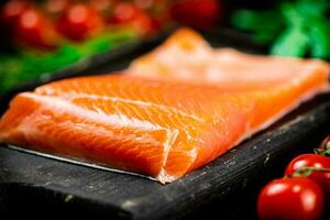 Salted salmon with greens and tomatoes on a cutting board. photo