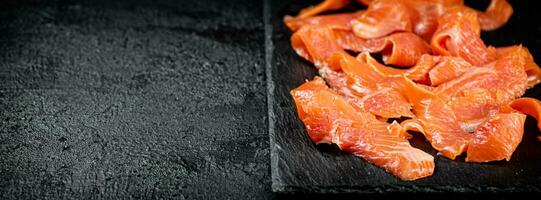 Pieces of salted salmon on a stone board. photo