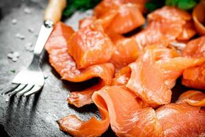 piezas de salado salmón con verdor en un Roca tablero. foto