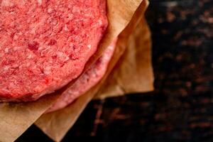 Raw burger on paper. On a rustic dark background. photo