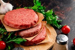 Raw burger on a wooden tray with tomatoes and dill. photo