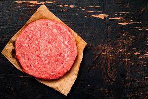 Raw burger on paper. On a rustic dark background. photo