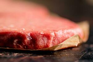 Raw burger on paper. On a rustic dark background. photo