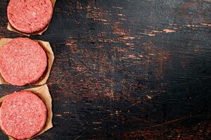 Raw burger on paper. On a rustic dark background. photo