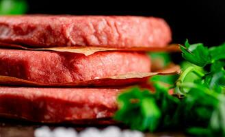 Raw burger on a table with greens and salt. photo