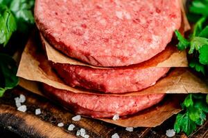 Raw burger on a cutting board with parsley and salt. photo