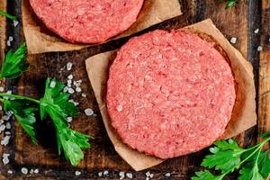 Raw burger on a cutting board with parsley and salt. photo