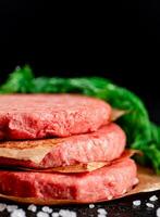 Raw burger on a table with greens and salt. photo