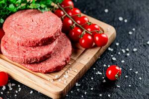 A raw burger on a tomato cutting board. photo