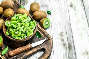 Kiwi slices in a bowl on a cutting Board with a knife. photo