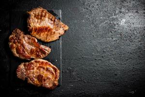 Delicious grilled pork steak on a stone board. photo