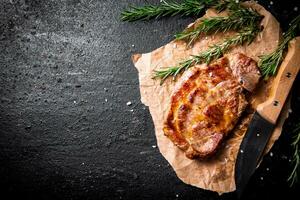 Grilled pork steak on paper with rosemary. photo