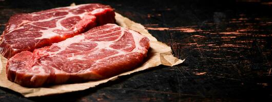 Raw pork steak on paper on the table. photo