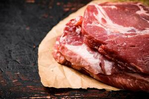 Raw pork steak on paper on the table. photo