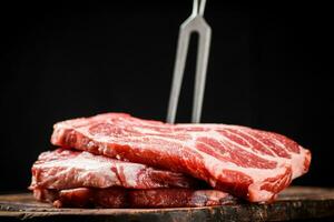 Raw pork steak on a cutting board with fork. photo