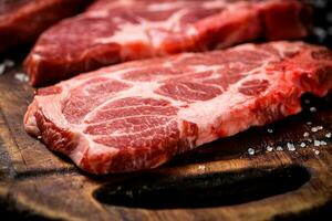 Raw pork steak on a wooden cutting board. photo