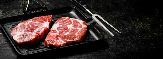 Raw pork steak on a grill pan. photo