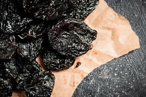 A bunch of delicious prunes on paper on the table. photo