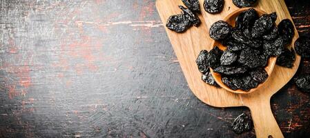 Prunes in a plate on a wooden cutting board. photo