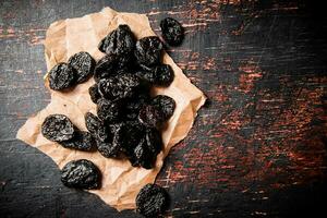 Prunes on paper on the table. photo