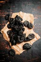 Prunes on paper on the table. photo