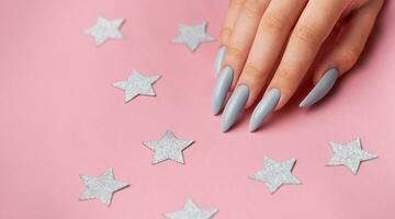 Hands with grey manicure on a pink background photo