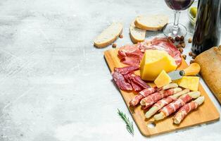 Antipasto background. Various meat and cheese snacks with red wine. photo