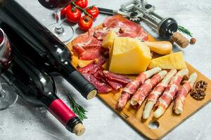 Antipasto background. Various meat and cheese snacks with red wine. photo