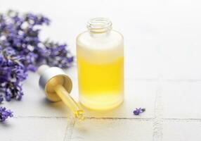 Lavender  natural essential oil and fresh lavender on a white tile background. photo