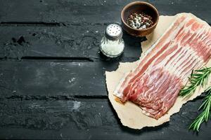 Raw bacon with rosemary and spices. photo