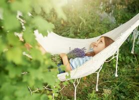 A little girl rests in a hammock  in the summer. photo