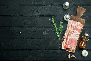 Raw bacon with rosemary branches. photo