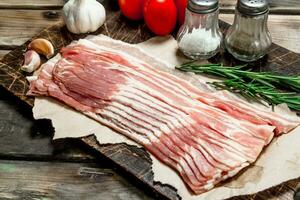 Raw bacon with vegetables, herbs and spices. photo