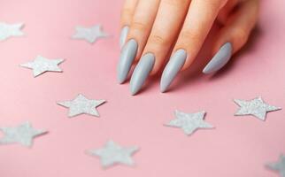 Hands with grey manicure on a pink background photo