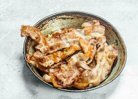 Fried bacon in a frying pan. photo