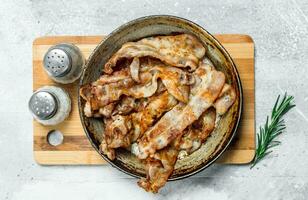 Fried bacon in a pan with spices. photo