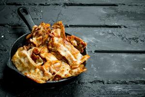 Fried bacon in a frying pan. photo