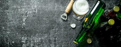 Beer in a glass and a glass bottle with opener. photo