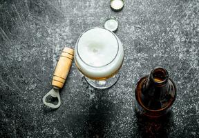 Beer in a glass with opener. photo