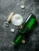 Beer in a glass and a glass bottle with opener. photo