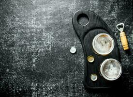 Beer in glasses on a black cutting Board with opener and covers. photo