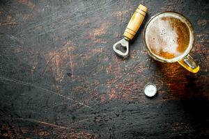 cerveza en un vaso taza y abrelatas. foto