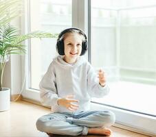 Cute little girl listening to music in headphones photo