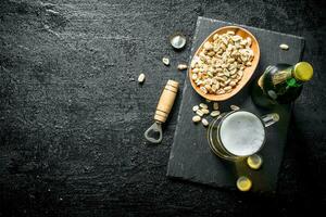 Beer in a glass and a bottle of peanuts in a bowl. photo