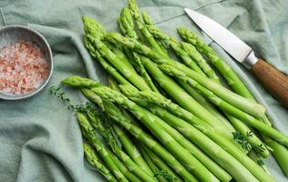 Bunch of raw asparagus stems with different spices photo